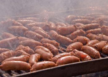 Sausages cooking on the grill in the background .